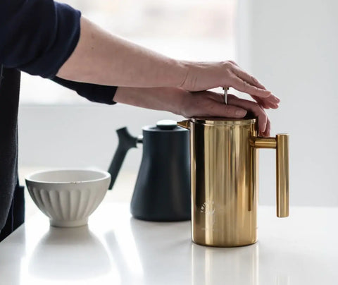 a person pressing down on a french press to show how to use a french press