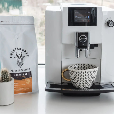 A close up of a Jura coffee machine for home and a bag of Sugarloaf espresso beans.
