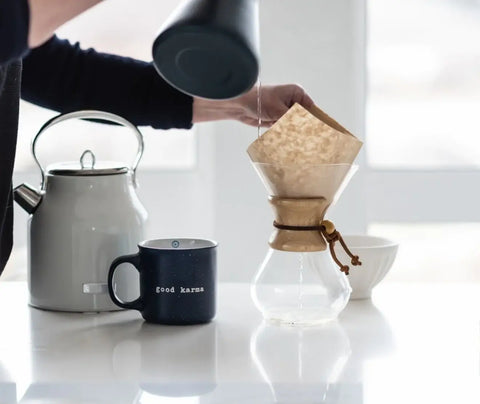 A person pouring water into a chemex coffee maker