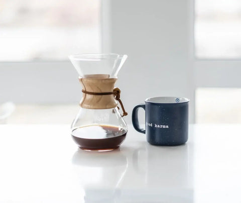 A chemex coffee maker and a coffee mug on a counter