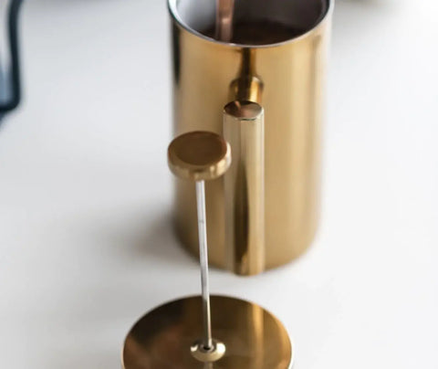a person stirring coffee in a french press to show how to use a french press